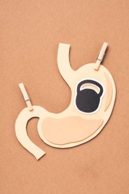 flat lay with human stomach with clothespins and symbol of kettlebell on beige clipart