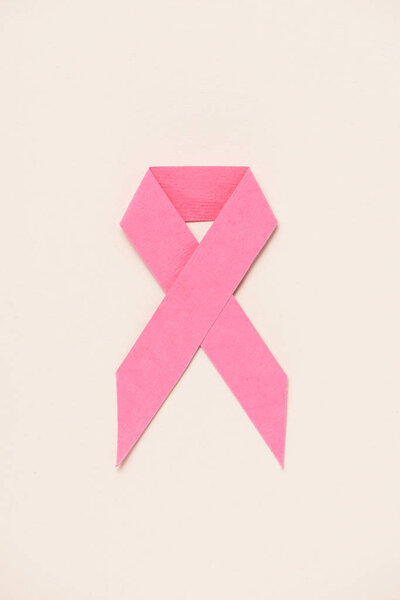 top view of breast cancer awareness pink ribbon on beige 
