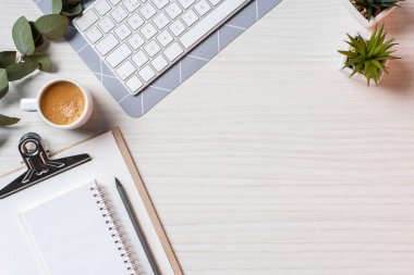 bilgisayar klavye, boş ders kitabı, kahve fincanı ve saksı bitkileri ofis masasında üstten görünüm 