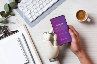 işadamı instagram masada kahve fincanı Office ile ekranda ile smartphone kullanarak cyborg el ile kısmi görünümü 