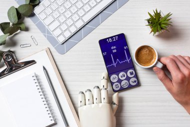 işadamı masada kahve fincanı Office ile ekranda tıbbi uygulama ile smartphone kullanarak protez kollu kısmi görünümü 