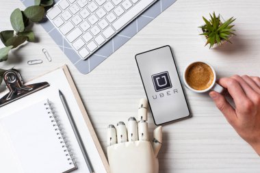 uber masada kahve fincanı Office ile ekranda ile smartphone kullanarak protez kollu işadamı resim kırpılmış 