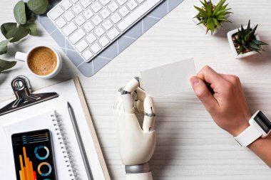 cyborg el ve Infographic ekranında Office ile smartphone ile masada boş ziyaret Kart tutan smartwatch ile işadamı kırpılmış görüntü 