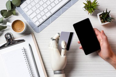 kredi kartı tutan ve ofiste tabloda boş ekran ile smartphone kullanarak protez kol ile işadamı resim kırpılmış 