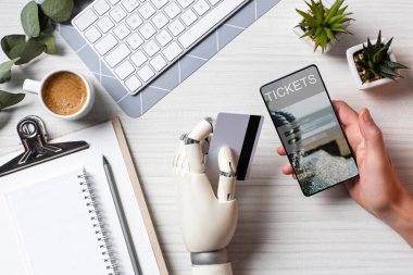 işadamı kredi kartı tutan ve ofiste tabloda ekranında bilet ile smartphone kullanarak protez kol ile kısmi görünümü 