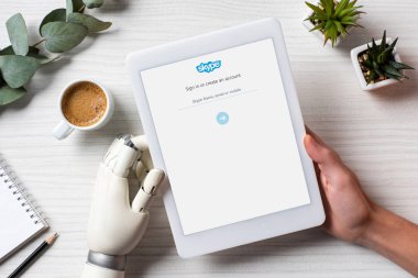 masada kahve fincanı Office ile ekranda skype ile dijital tablet kullanarak cyborg kollu adam resim kırpılmış 