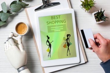 kredi kartı tutan ve dijital tablet masa kahve fincanı Office ile ekranda en iyi alışveriş ile kullanma cyborg el ile işadamı kırpılmış görüntü 