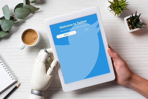 частичный взгляд бизнесмена с протезной рукой с помощью цифрового планшета с билетами на экране за столом с чашкой кофе в офисе
 