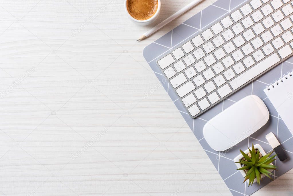 top view of arranged coffee cup, blank textbook, computer mouse and keyboard at table in office 