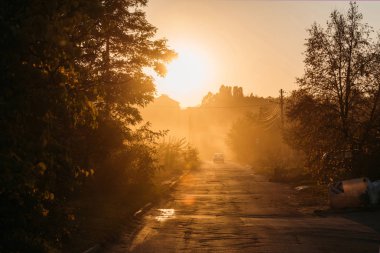 beautiful orange sunrise above trees and car on road clipart