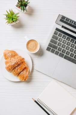 laptop, boş ders kitabı, kruvasan ve kahve Kupası Office ile çalışma alanı'nın üstten görünüm 