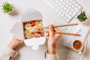 Kahve Kupası ve bilgisayar klavye Office ile masada yemek çubukları tarafından noodle yemek işkadını kırpılmış görüntü 