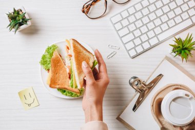 sandviç ve kahve ile öğle yemeği masada gülümseme Office sembolü ile kağıt bardak sahip işkadını kırpılmış görüntü 