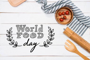 Cherry tomatoes with wooden spatula and salt grinder with table cloth on tabletop, world food day inscription clipart