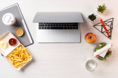 dizüstü bilgisayar, sağlıklı yiyecek ve abur cubur işyerinde üstten görünüm
