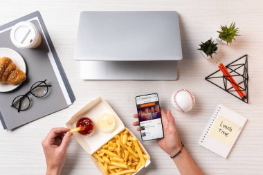 Ketçap ile patates kızartması yemek ve işyerinde soundcloud app ile smartphone kullanarak kişi resmini kırpılmış