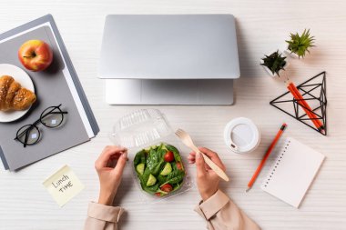 dizüstü bilgisayar ve ofis malzemeleri ile işyerinde sebze salata yemek kişinin kırpılmış atış