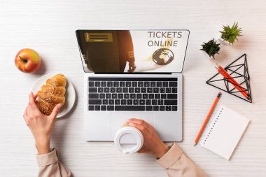 Tek kullanımlık kahve ve kruvasan bilet online web sitesi ile dizüstü bilgisayar kullanırken tutan işkadını kırpılmış atış