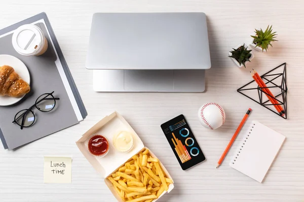 フライド ポテト 昼食時の碑文と付箋の平面図パソコンと職場でチャートとスマート フォン — ストック写真