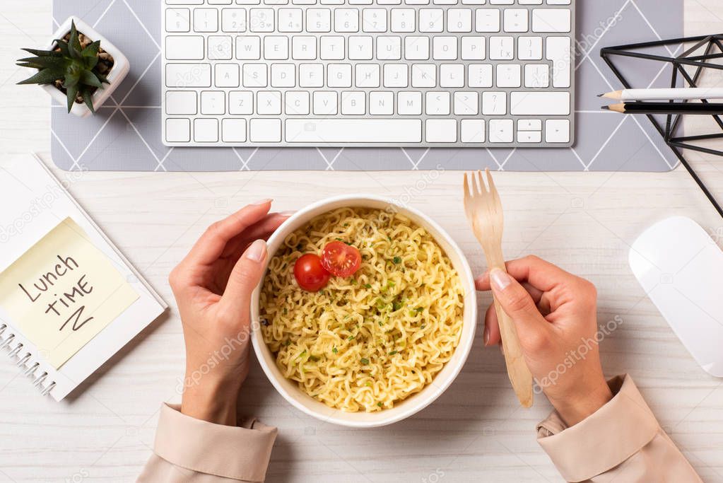 cropped shot of person eating noodles at workplace