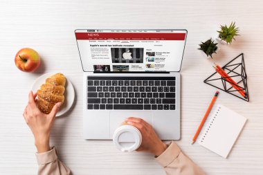 bbc haber sitesi ile dizüstü bilgisayar kullanırken tek kullanımlık kahve ve kruvasan tutan işkadını kırpılmış atış
