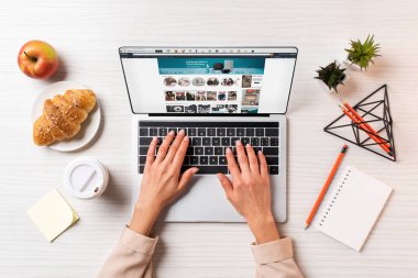 iş kadını masada kahve, elma ve kruvasan ile amazon Web ile dizüstü bilgisayar kullanarak kırpılmış atış        