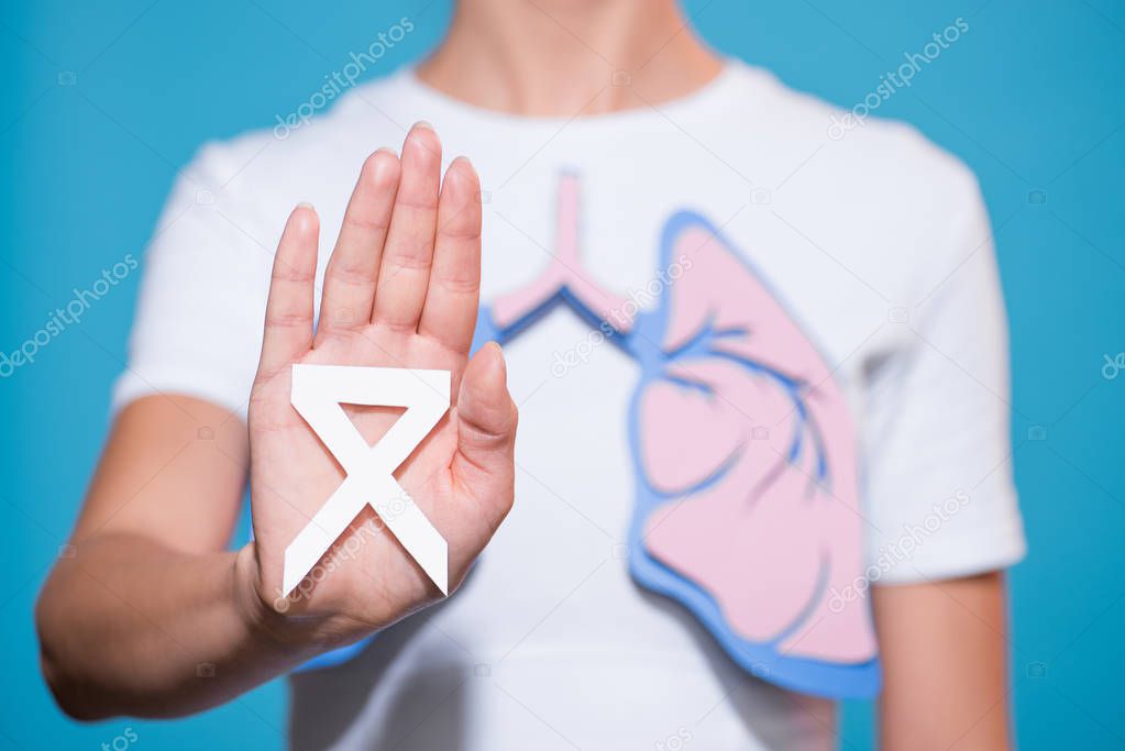 partial view of woman with paper made lungs showing lung cancer awareness white ribbon on blue backdrop