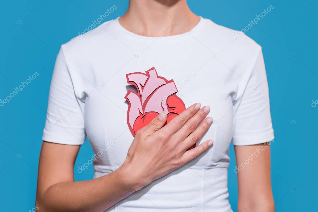 cropped shot of woman in white tshirt with paper made heart on blue backdrop