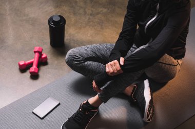 Sportif kadın kopya alanı ile smartphone ile sportif mindere oturmuş görünümünü kırpılmış