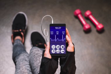 Smartphone ile spor uygulama tutan kadın görünümünü kırpılmış