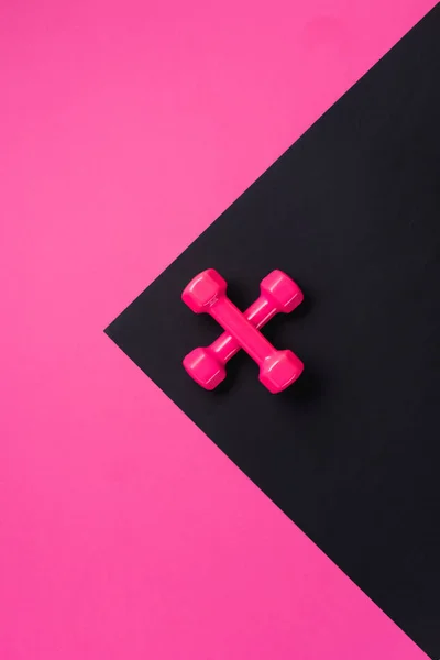 顶部视图两个交叉哑铃在黑色和粉红色的背景与复制空间 — 图库照片