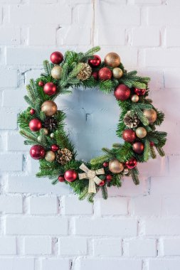 Beyaz tuğla duvara asılı Noel çelenk