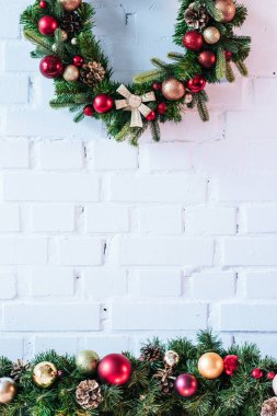 Arka plan beyaz tuğla duvar üzerine Noel topları ile Noel çelenk