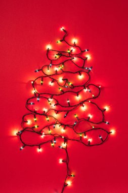 Kırmızı bir arka plan üzerinde Noel ağacı şeklinde renkli çelenk 