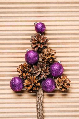 Mor Noel topları ve çam kozalakları dokulu arka plan üzerinde Noel ağacı şeklinde düz yatıyordu