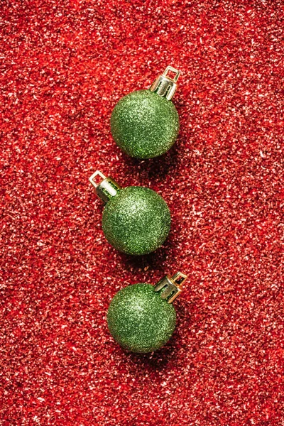 赤スパンコールの背景に緑色の光沢のある装飾的なクリスマス ボールのトップ ビュー — ストック写真