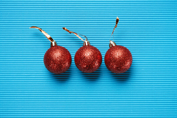 Flat lay of three red shiny decorative christmas balls on blue textured background — Stock Image Flat Lay Three Red Shiny Decorative Christmas Balls Blue Textured Royalty Free Stock Photos