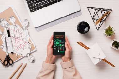 Ofis Masası smartphone ekranında, düz app pazarlama ile holding laptop ve kadın eller ile yatıyordu