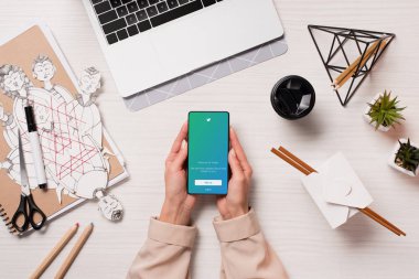 Ofis Masası twitter uygulaması ile akıllı telefon ekranında, düz tutarak laptop ve kadın elleriyle yatıyordu