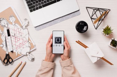 Ofis Masası uber app ile akıllı telefon ekranında, düz tutarak laptop ve kadın elleriyle yatıyordu