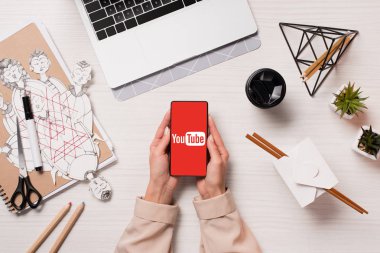 Ofis Masası youtube uygulaması ile akıllı telefon ekranında, düz tutarak laptop ve kadın elleriyle yatıyordu