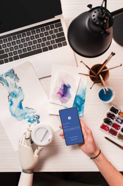 smartphone ile facebook app ekranda tutan robot el ile görünümü tasarımcısının ofis masası, kırpılmış