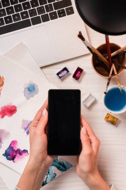 Kırpılan görünümü tasarımcısının smartphone ile boş ekran, düz tutarak ofis masası, lay