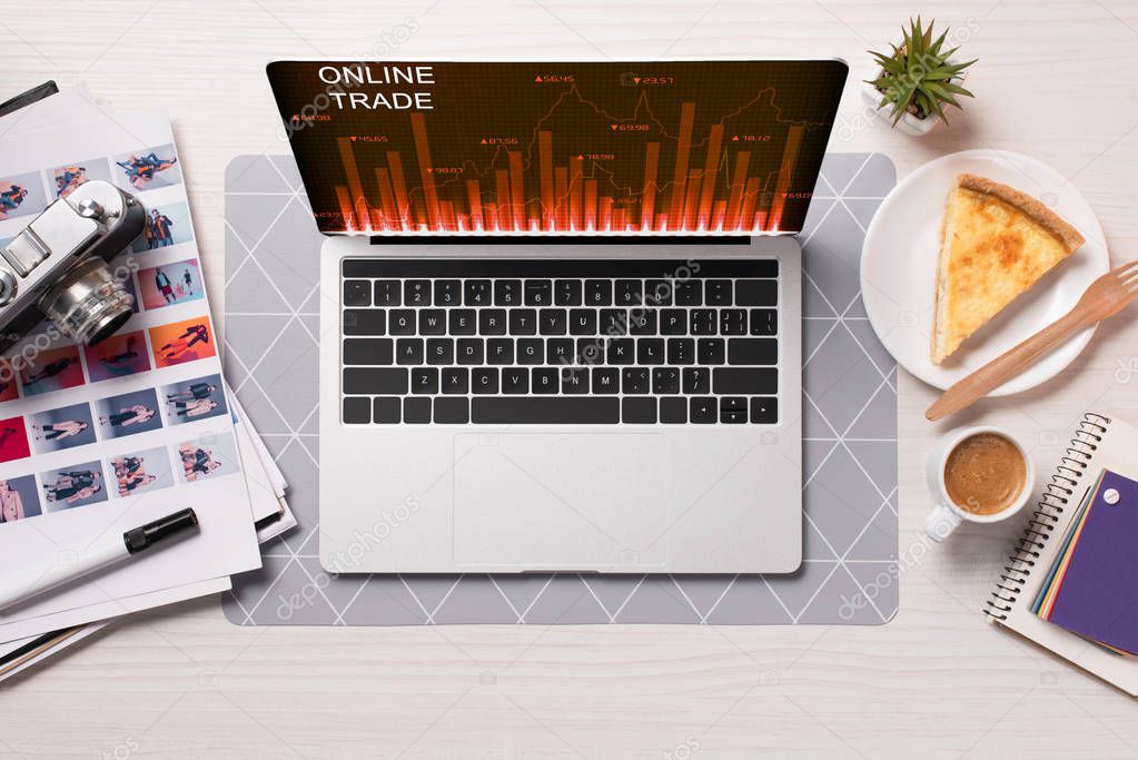 Office desk with laptop with online trading website on screen, flat lay