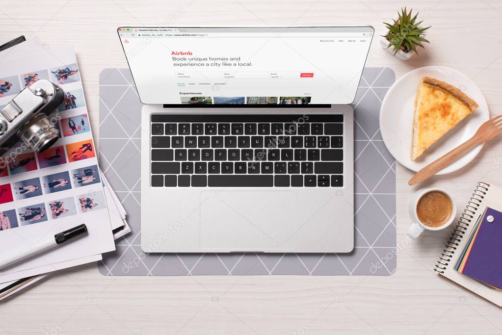 Office desk with laptop with airbnb website on screen, flat lay