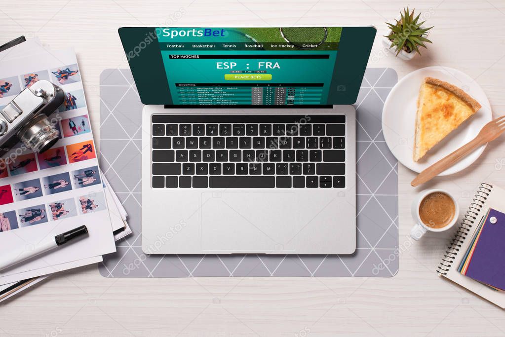 Office desk with laptop with sports betting website on screen, flat lay