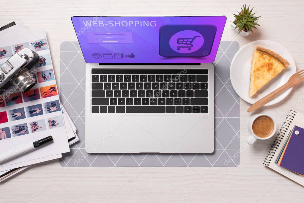 Office desk with laptop with shopping website on screen, flat lay