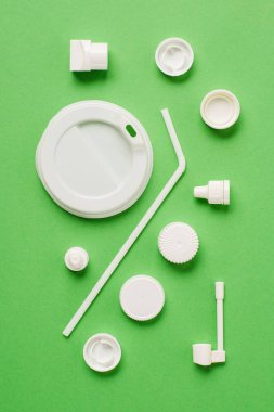 Plastik şişe kapakları, saman ve kapak için içki içme yeşil arka plan üzerinde üstten görünüm