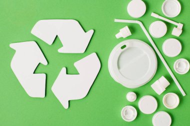Yeşil arka plan üzerinde geri dönüşüm işareti ve tek kullanımlık plastik çöp farklı türde üstten görünüm