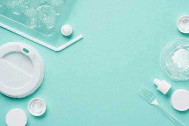 Plastik şişe kapakları, saman, çatal, yumurta tepsi ve içki için kapak üzerinde mavi arka plan içme üstten görünüm